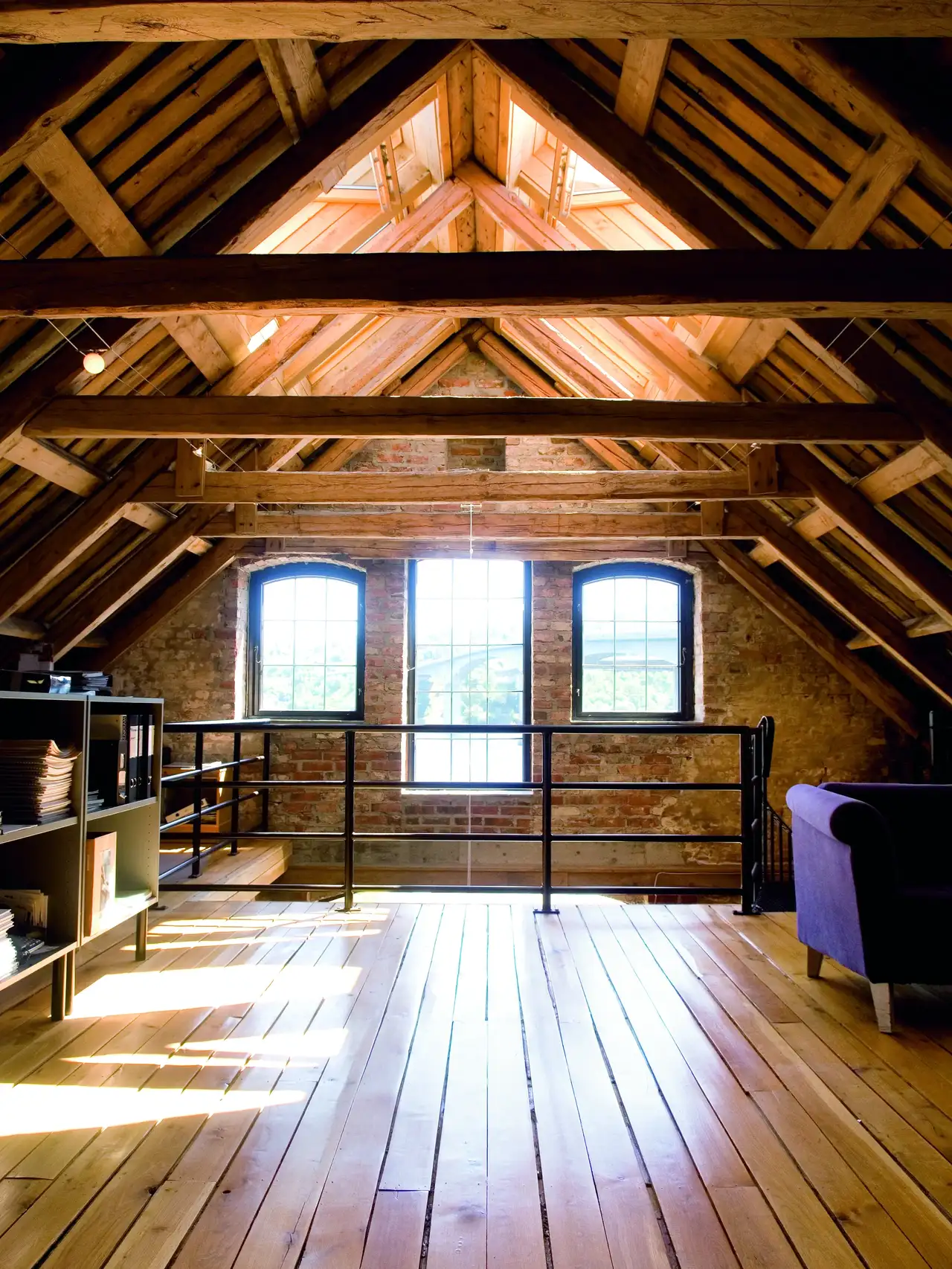 Mansarda con pavimento e soffitto in legno, con travi esposte e finestre verticali e per tetti