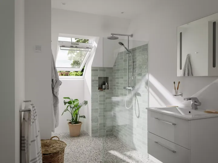 Modernes Badezimmer mit VELUX Dachflächenfenster, grün gefliester Dusche und Terrazzoboden.
