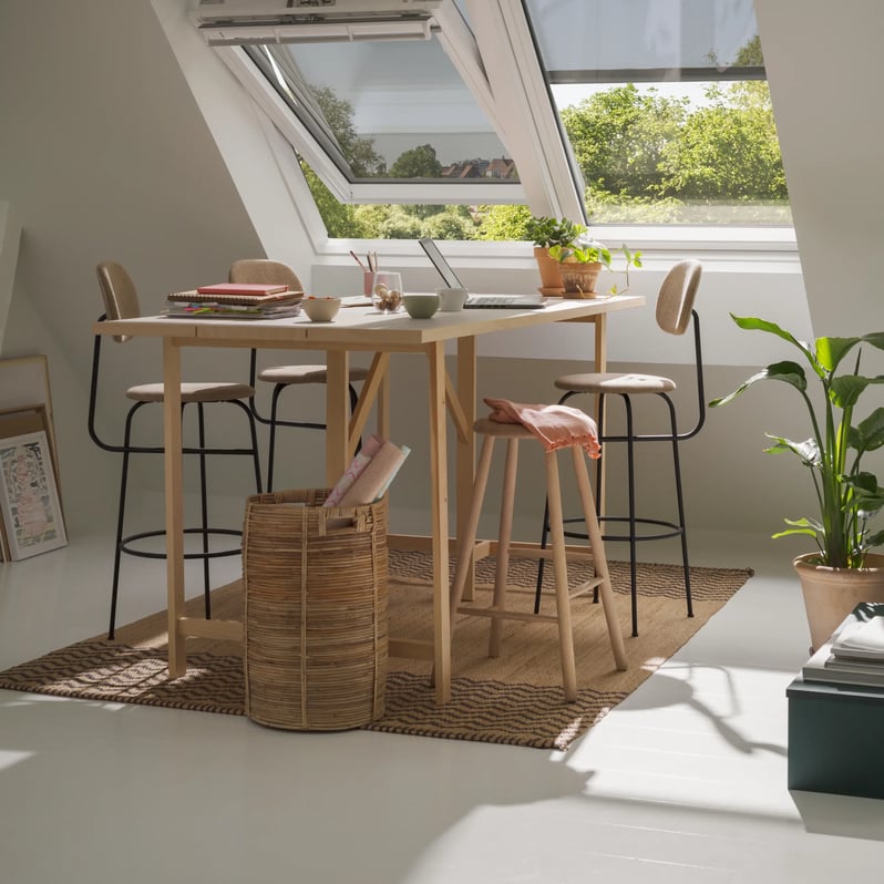 Attic workspace with sloped ceiling and VELUX roof windows, and awning blind, natural light entering and fresh air.