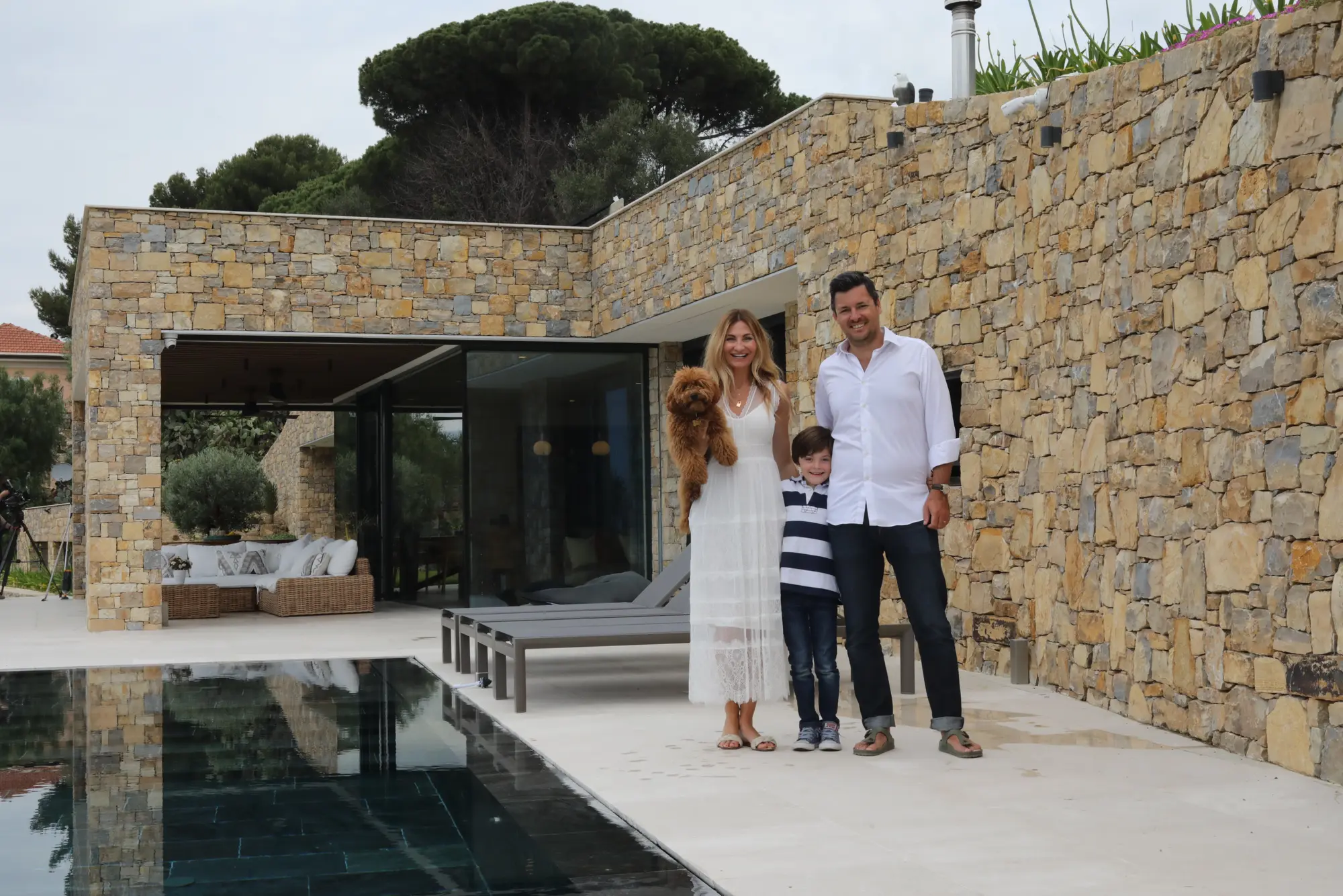 Man, woman and dog in next to a pool at their home