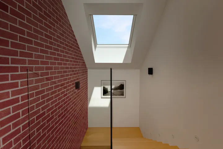 Chodba s červenou cihlovou stěnou a střešním oknem VELUX | VELUX