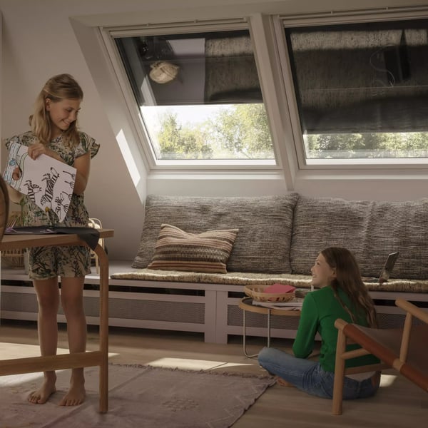 Attic playroom with sloped ceiling, VELUX roof windows, and children playing.