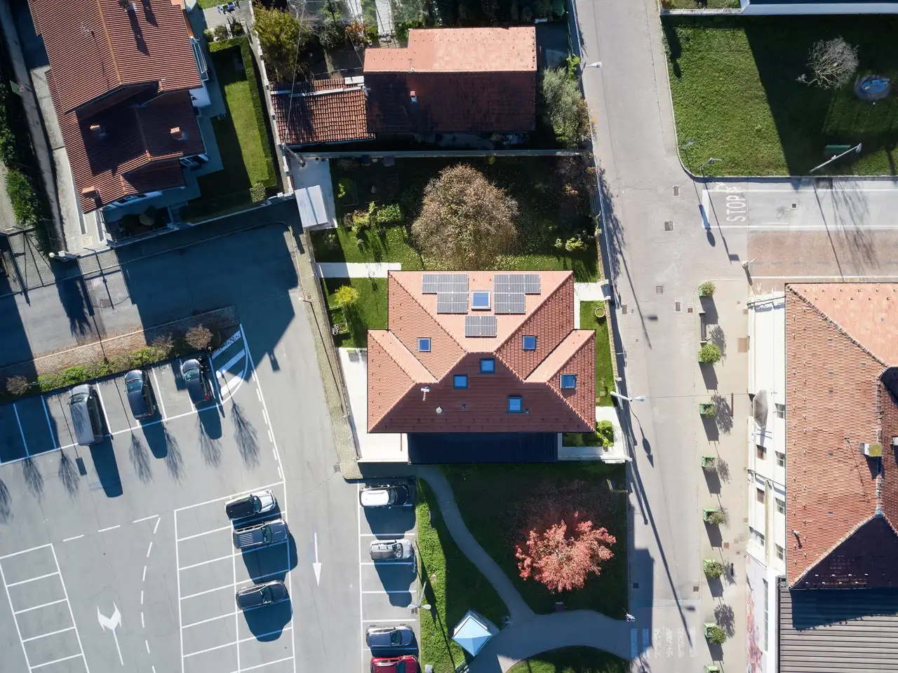 Luchtfoto van een huis met rood pannendak en zonnepanelen in een woonwijk.
