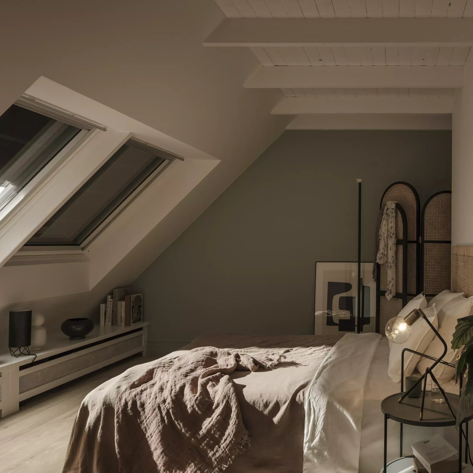 Attic bedroom with sloped ceiling and VELUX roof window, cozy decor.