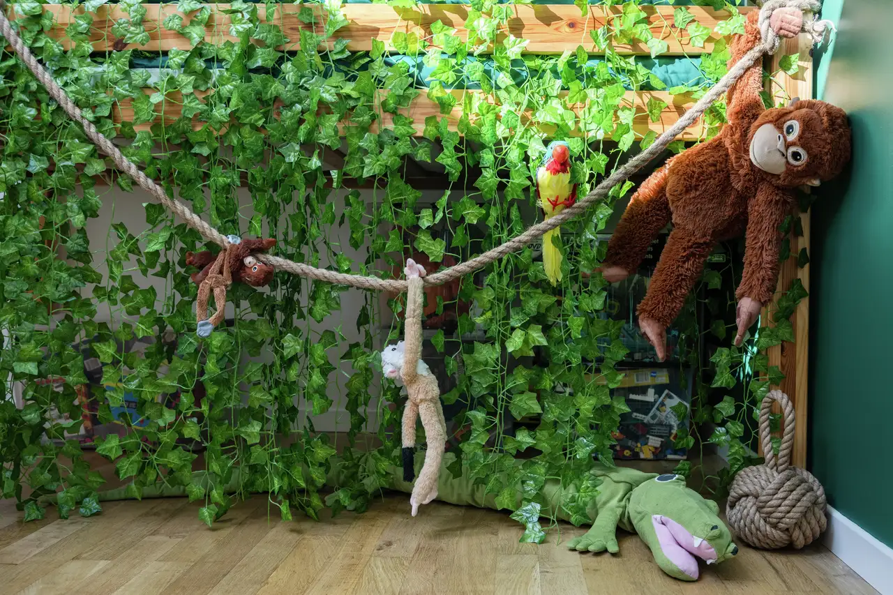 Kids room with jungle-themed decor, plush toys and leafy vines