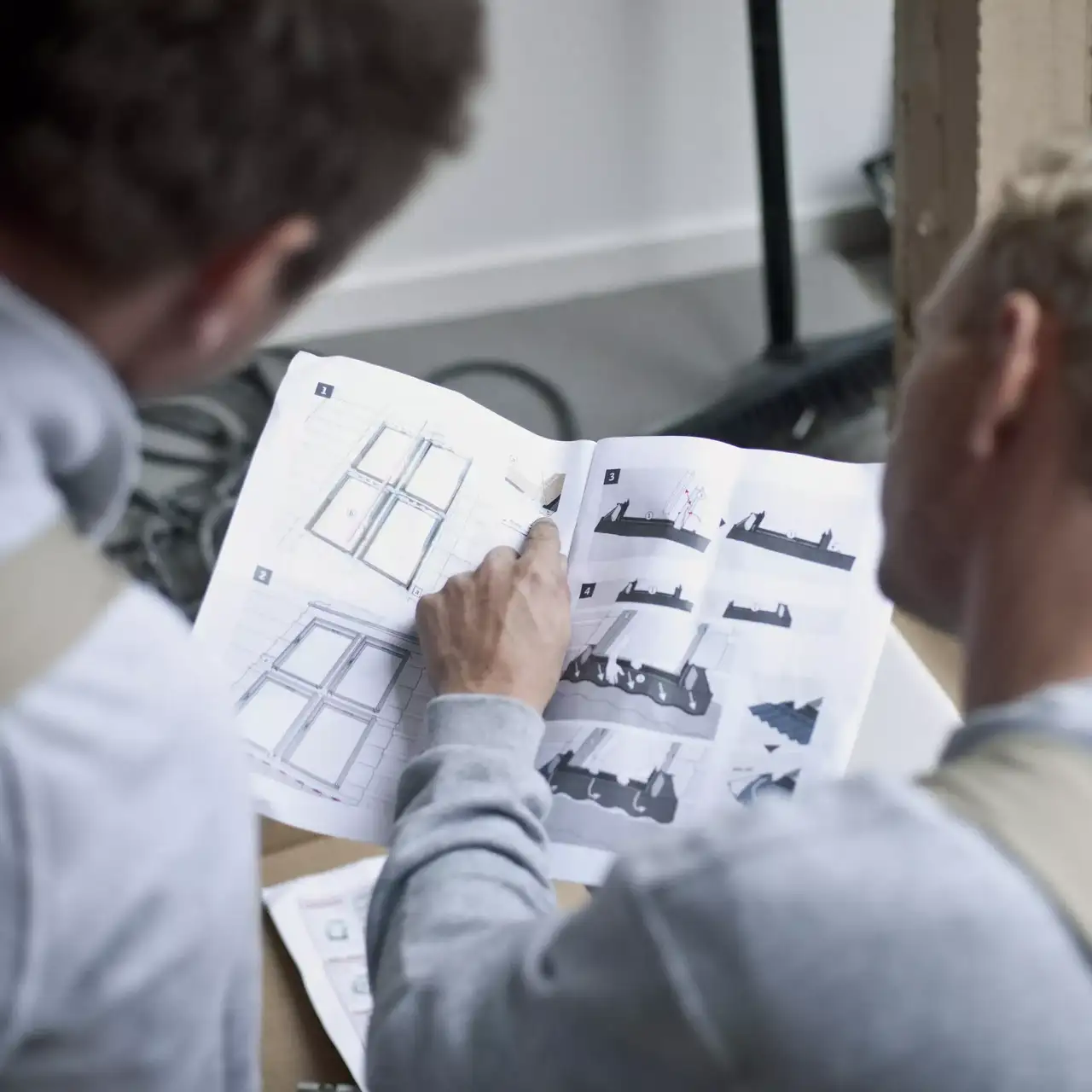 Handwerker studieren eine Einbauanleitung für den Einbau von VELUX Dachfenstern