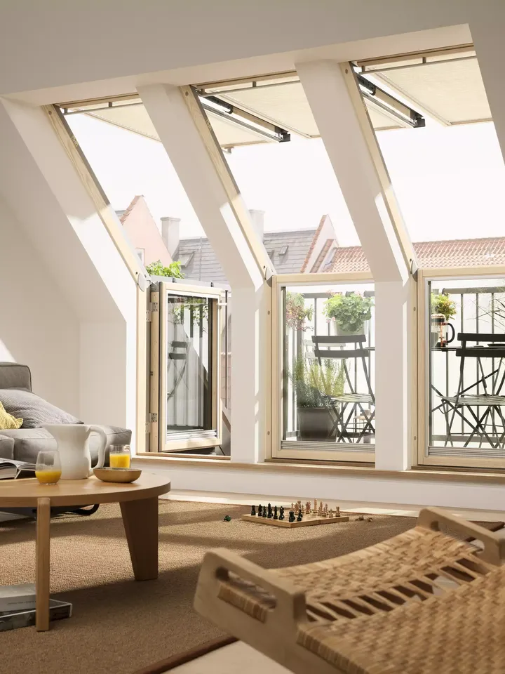 Gemütliches Wohnzimmer im Dachboden mit offenen VELUX Dachflächenfenstern und bequemer Einrichtung.