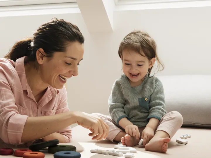 Junge Mutter spielt Domino mit ihrer kleinen Tochter auf dem Kinderzimmerboden | VELUX Magazin