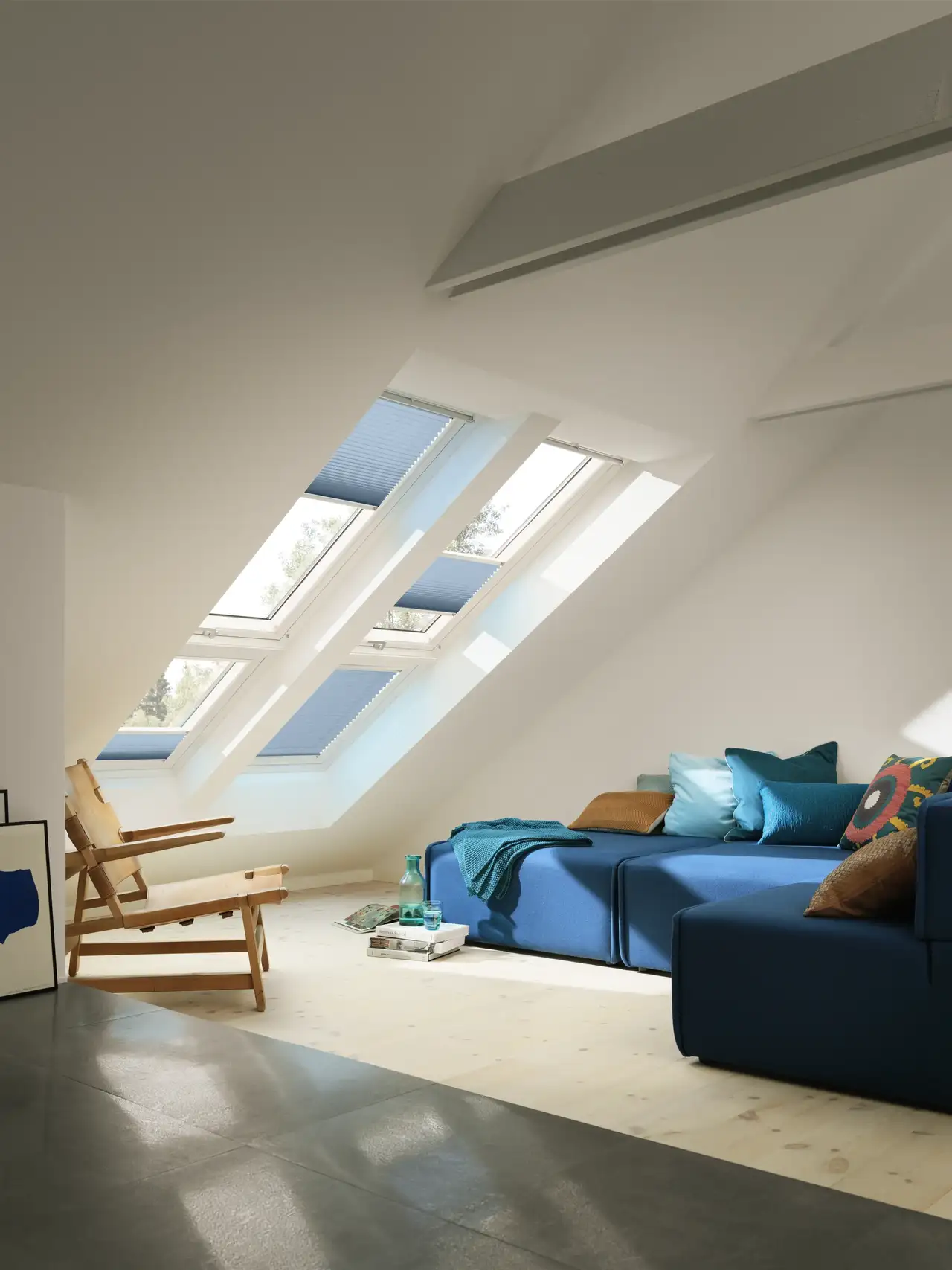 Séjour mansardé équipé de fenêtres de toit VELUX et de stores plissés bleus filtrant la lumière naturelle 