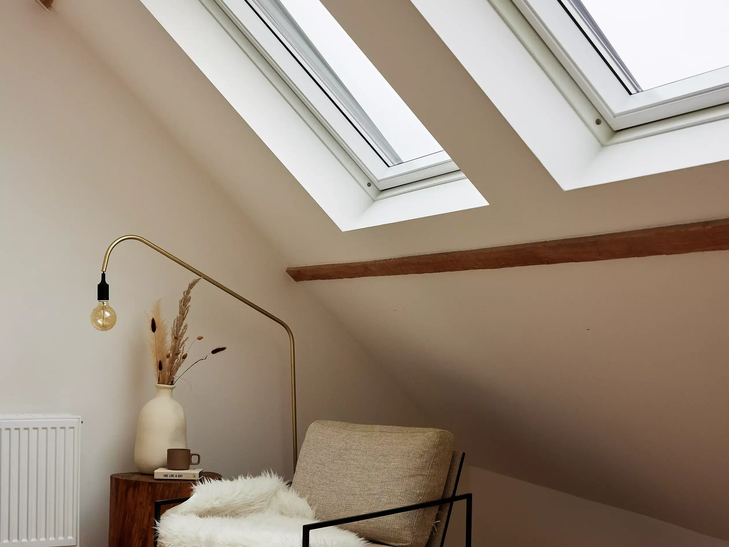 Fauteuil avec couverture et lampe dans un salon sous des fenêtres de toit.