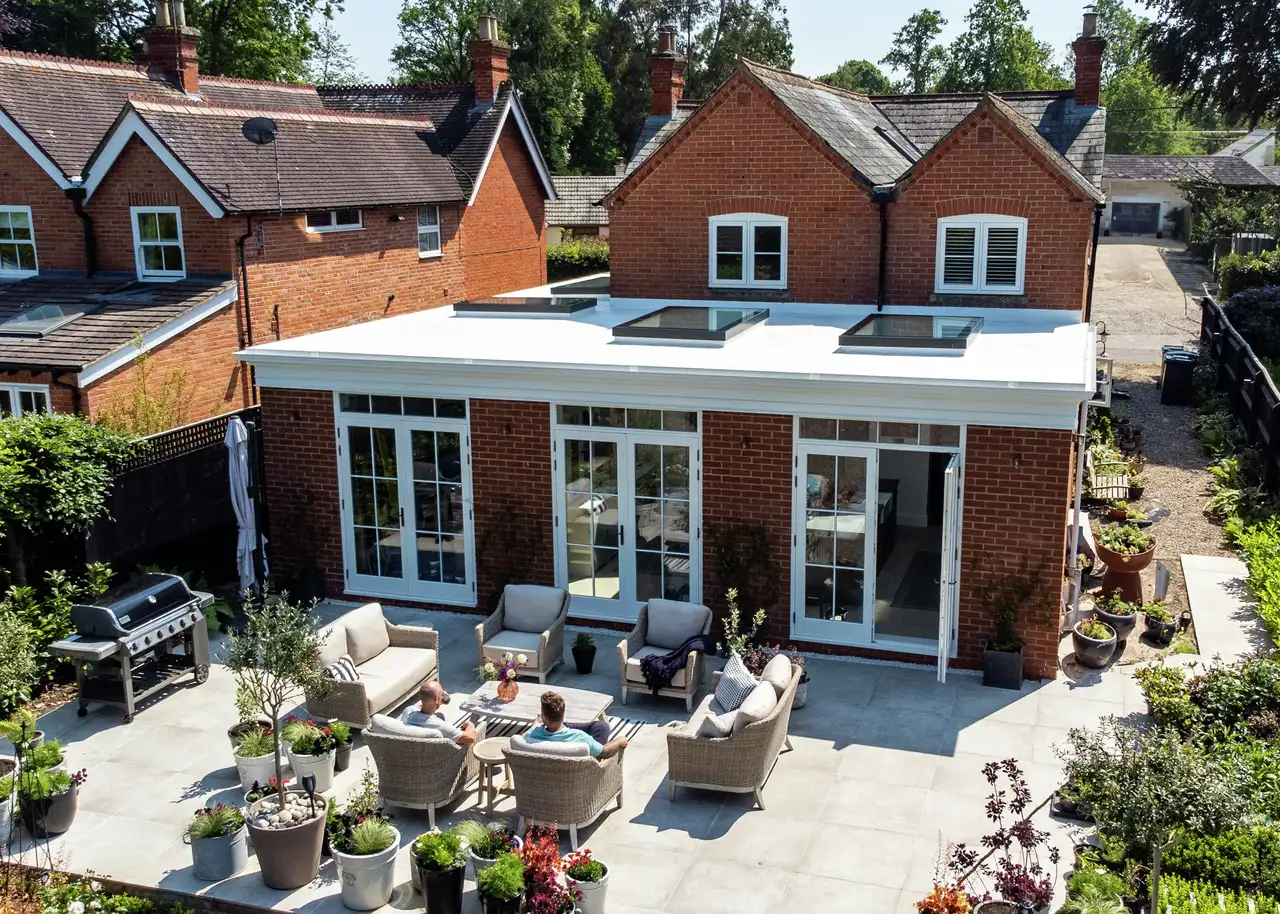 Residential building with modern extension, flat roof, VELUX roof windows, outdoor seating