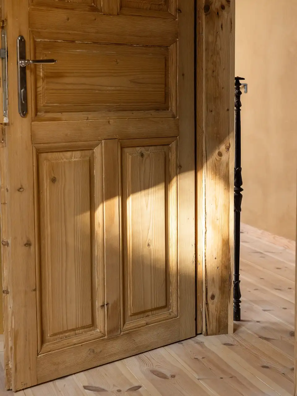 Partially open wooden door with sunlight illuminating the wood grain. 