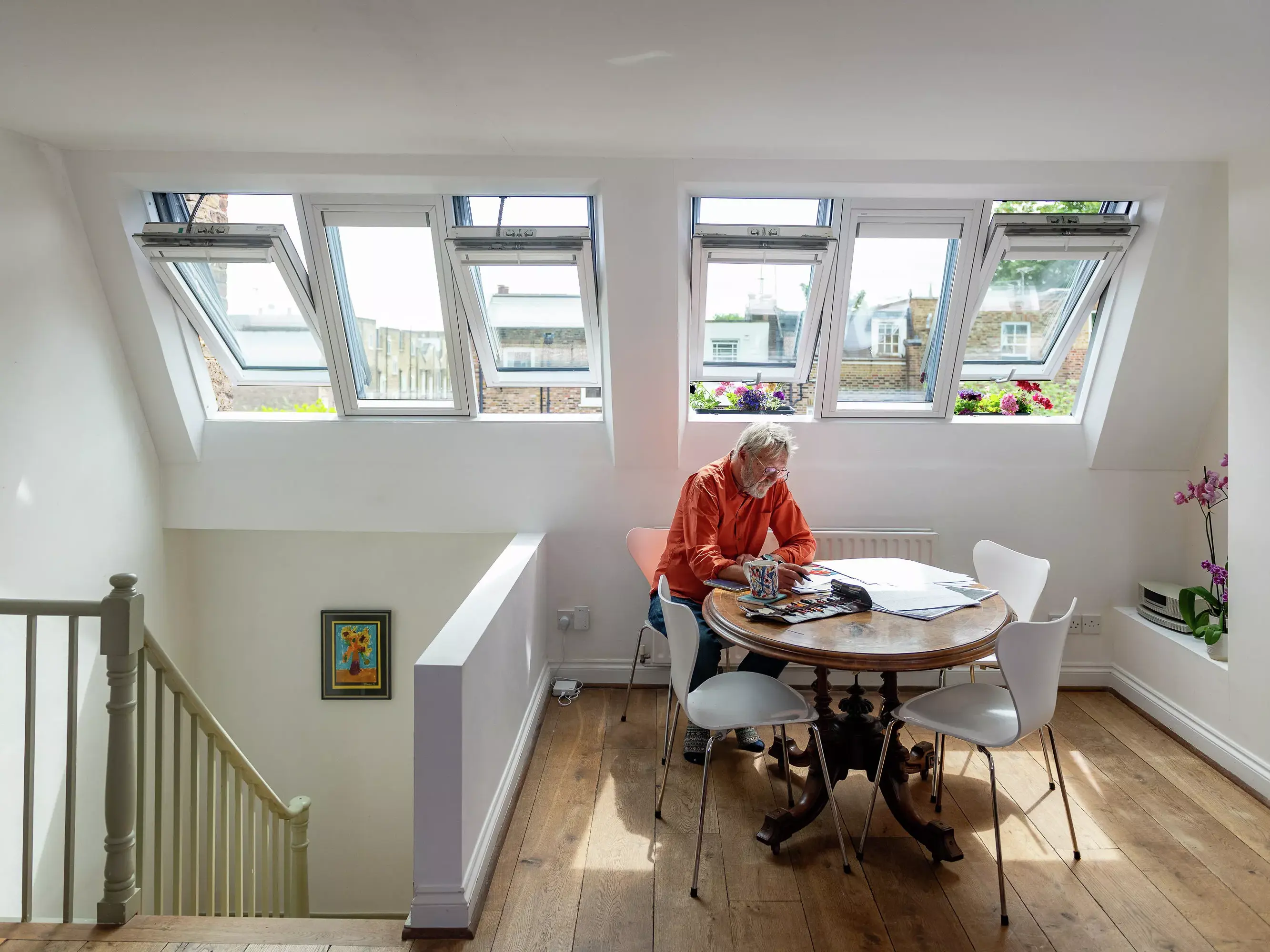 Espace repas confortable dans le comble avec lumière naturelle provenant des fenêtres de toit VELUX et une table ronde.