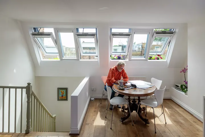 Dachboden-Essbereich mit VELUX Dachflächenfenstern und einem runden Tisch unter natürlichem Licht.