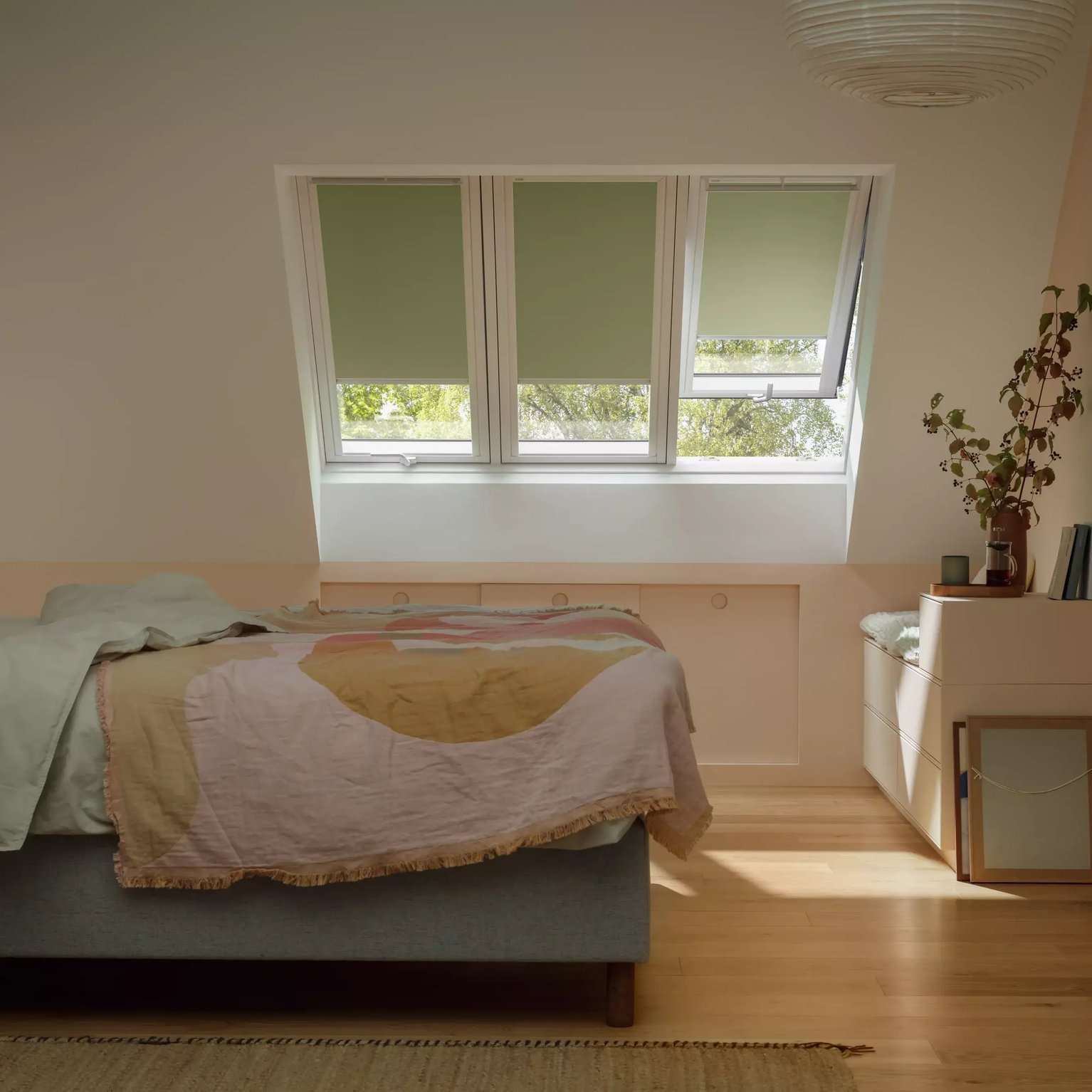 Attic bedroom with sloped ceiling and VELUX roof window, warm decor.