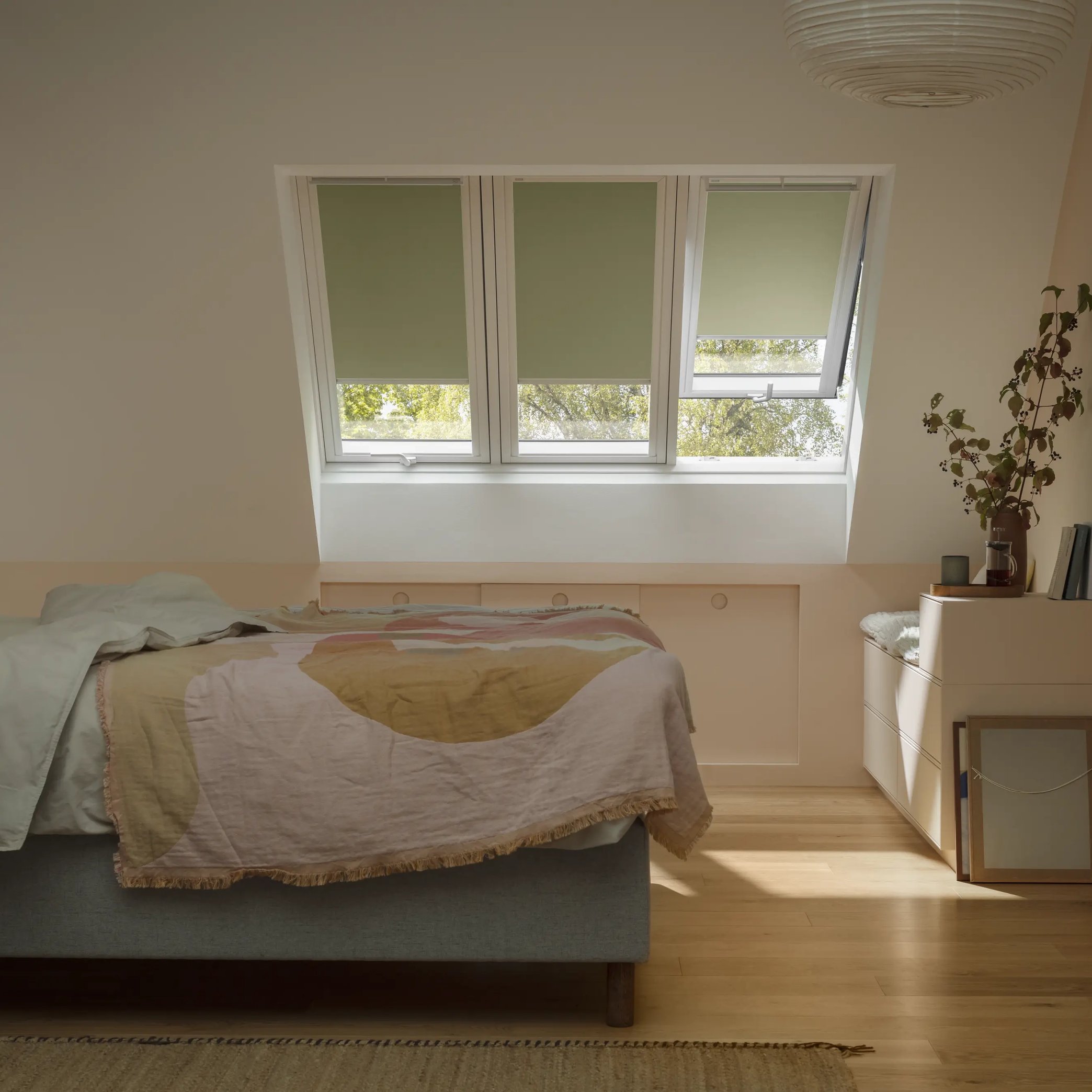 Attic bedroom with sloped ceiling and VELUX roof window, warm decor.