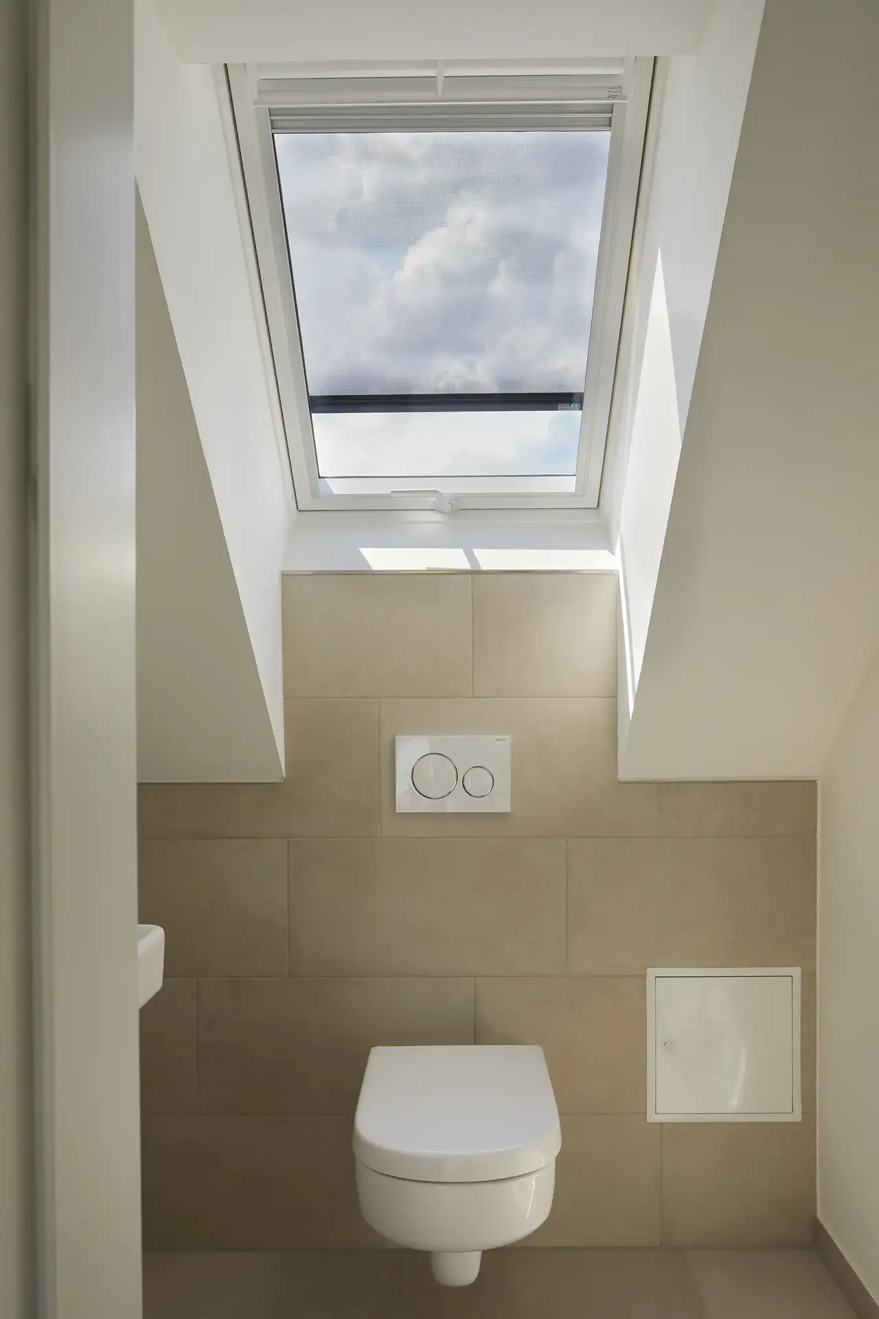 Particolare di un sanitario in un bagno in mansarda, con una finestra per tetti a illuminare il bagno.