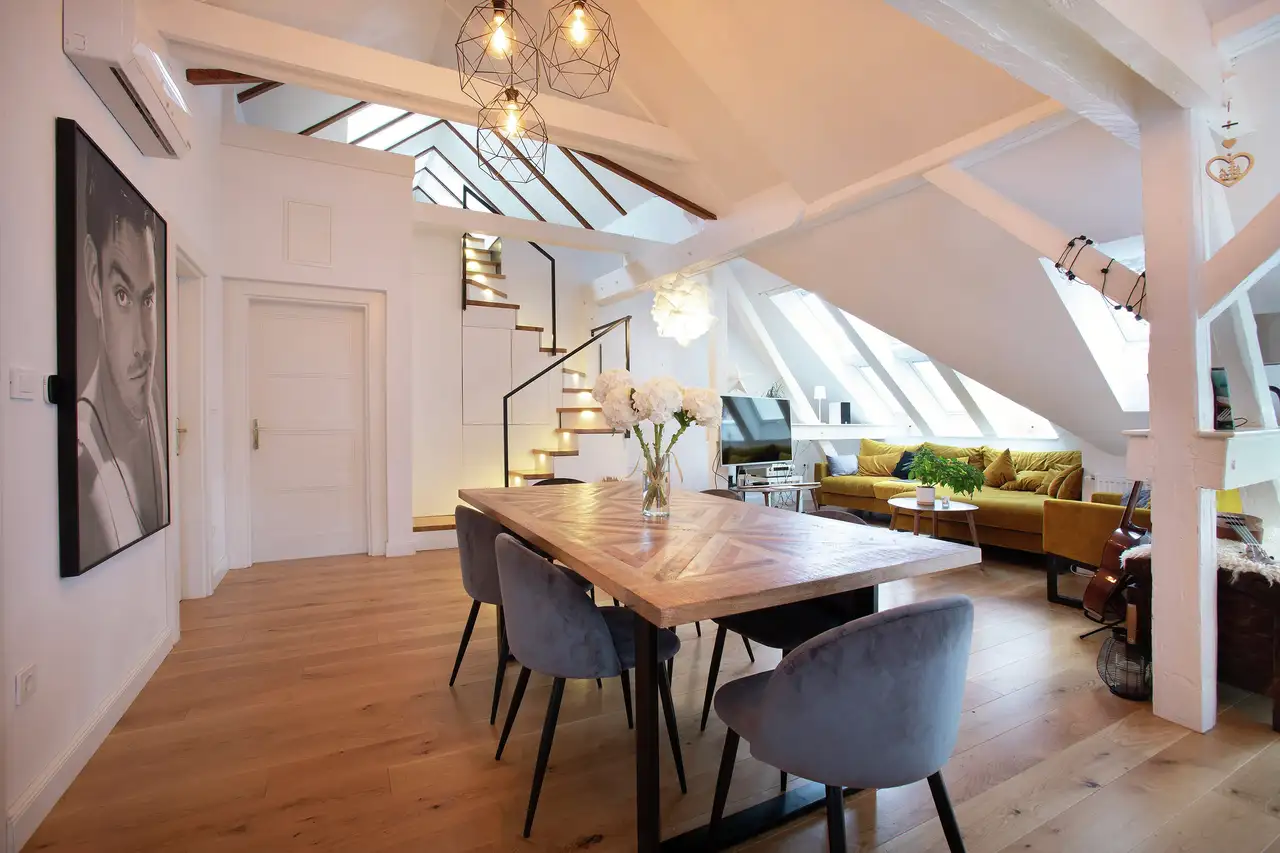 Stylish dining area in an attic with roof windows, modern decor, and wooden elements | VELUX