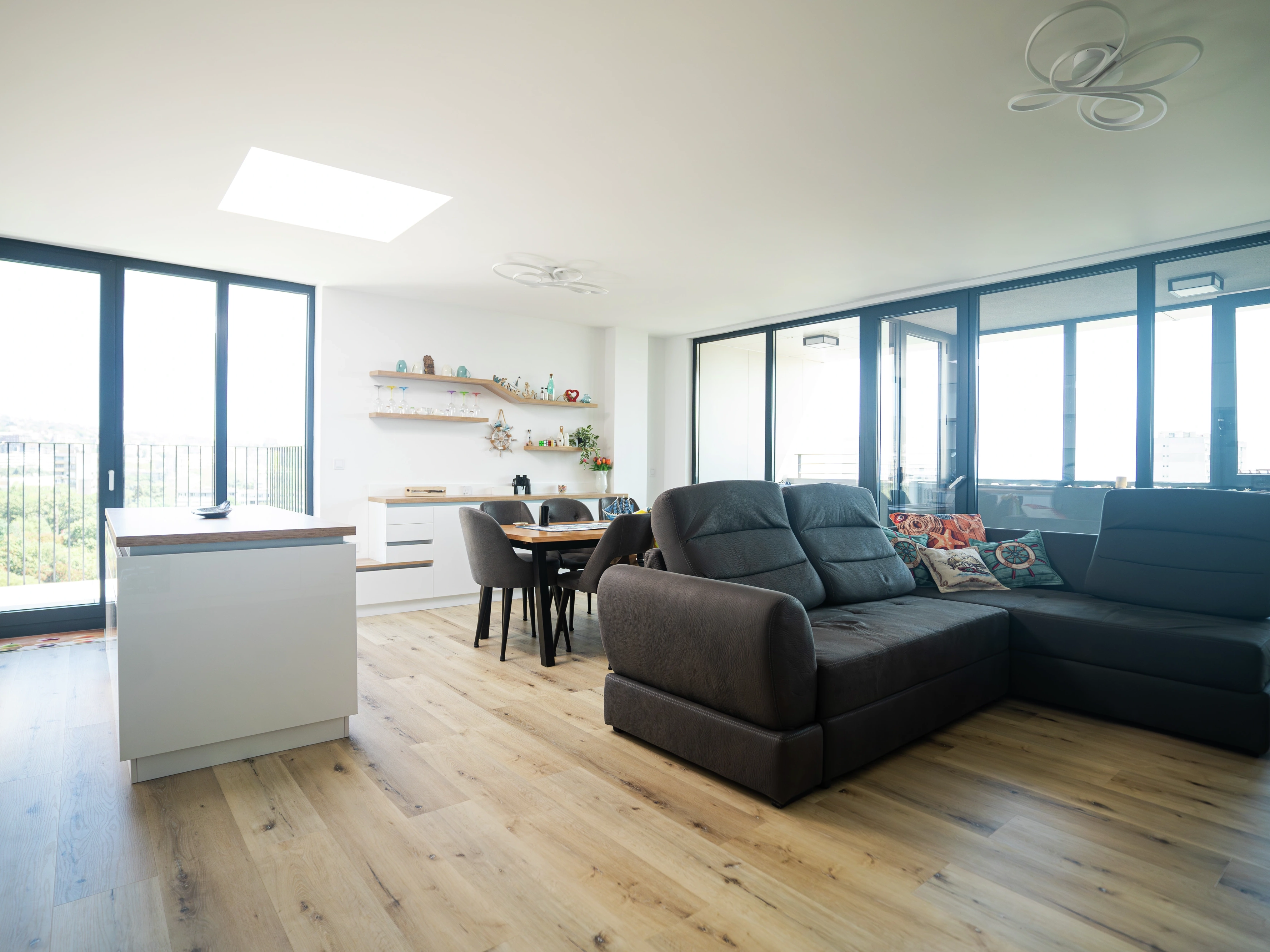 Sunny open-plan living room and kitchen with VELUX flat roof window and balcony views.