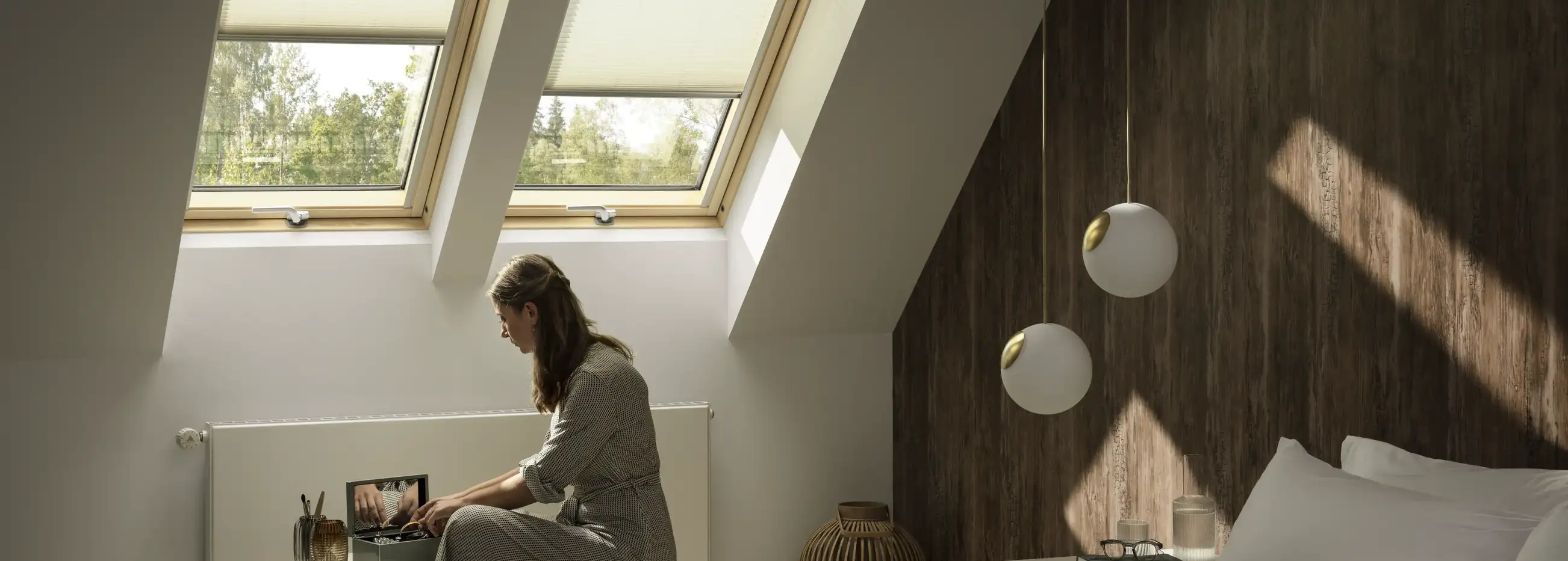 Attic bedroom with sloped ceiling and VELUX roof windows, natural light entering.