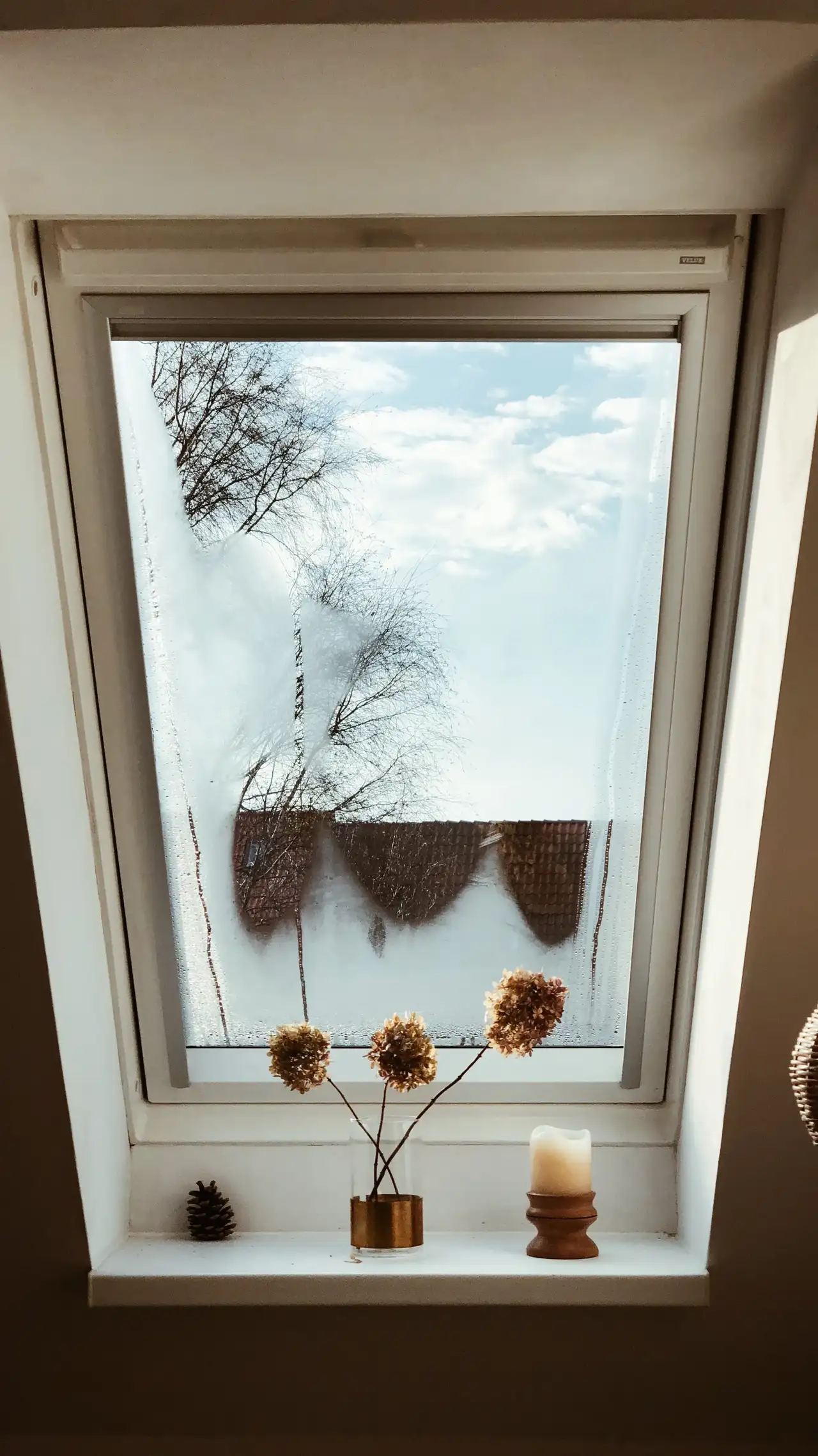 VELUX çatı pencereli çatı katı, denizlik üzerinde kurutulmuş çiçekler ve bir mum. 