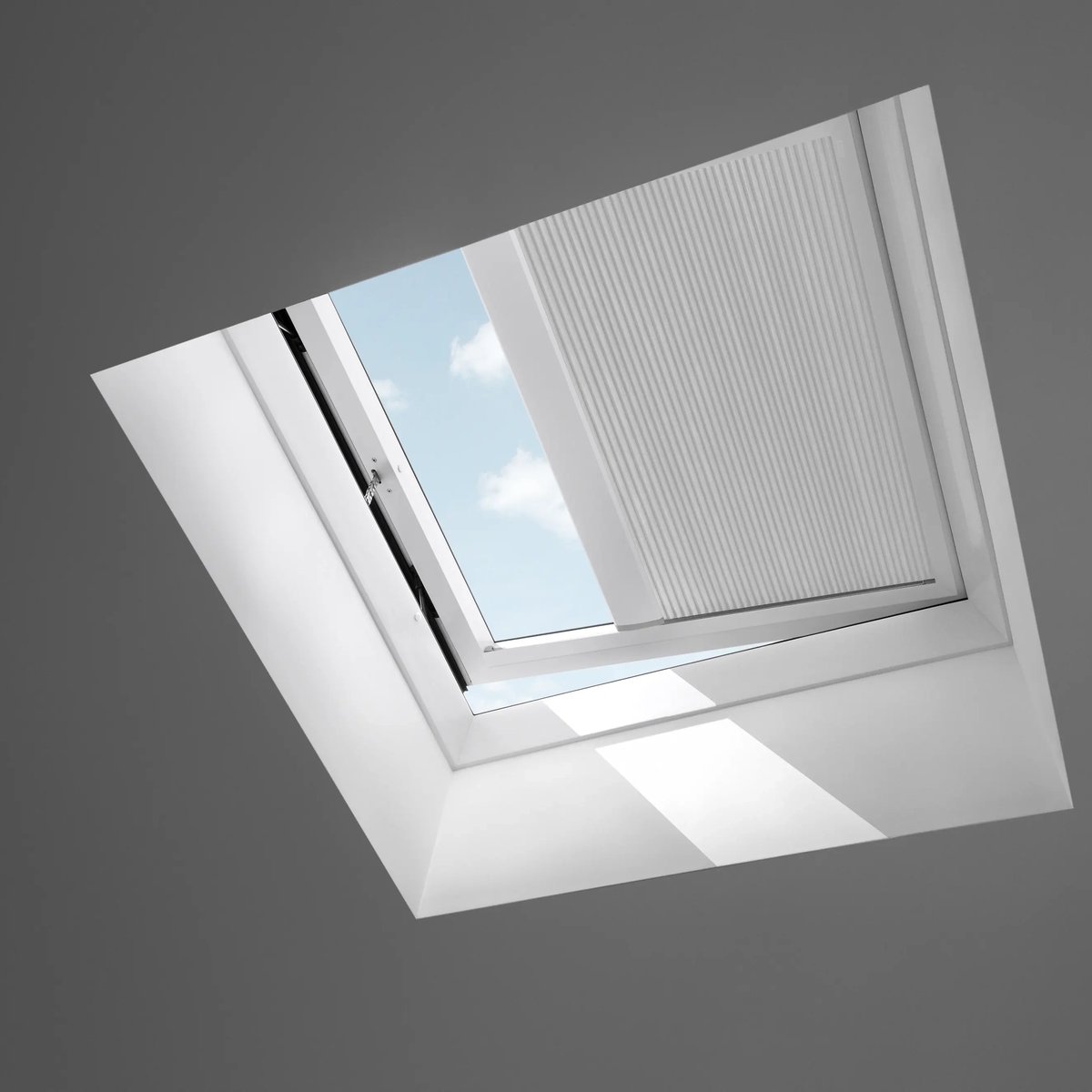 Open VELUX roof window on a sloped ceiling, sky view visible.