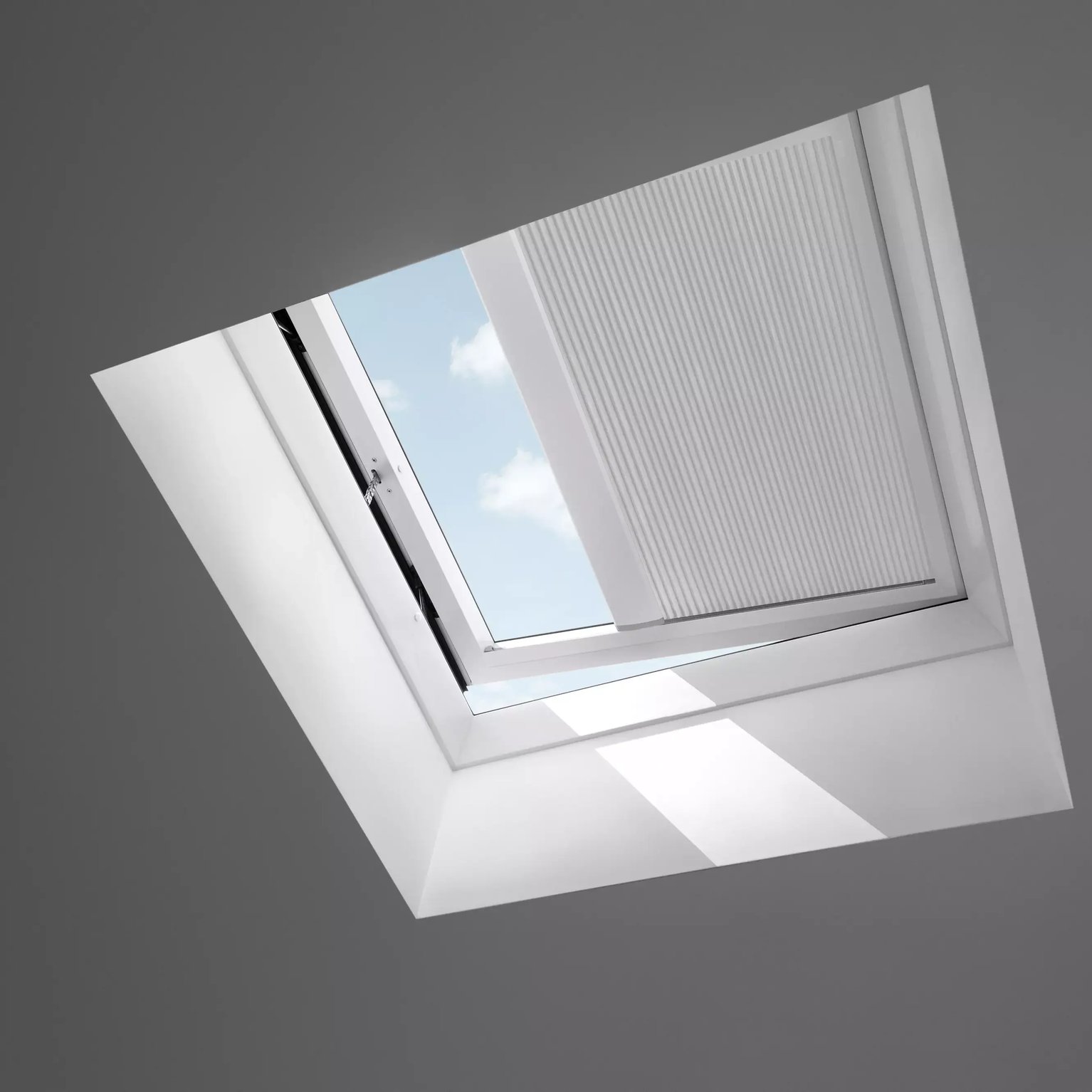 Open VELUX roof window on a sloped ceiling, sky view visible.