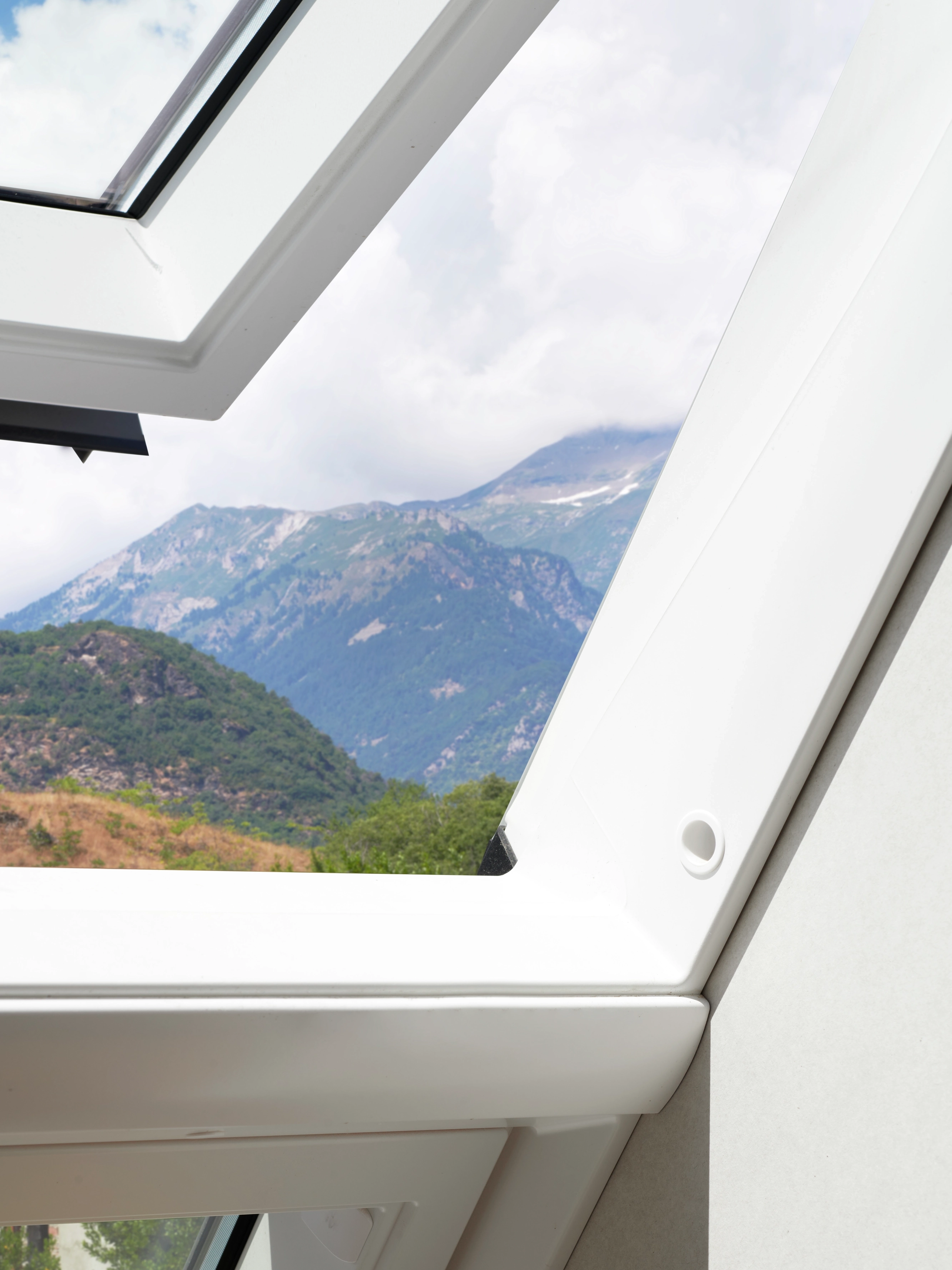 Panorama alpino mozzafiato visto da una finestra per tetti VELUX, che porta la natura dentro casa.