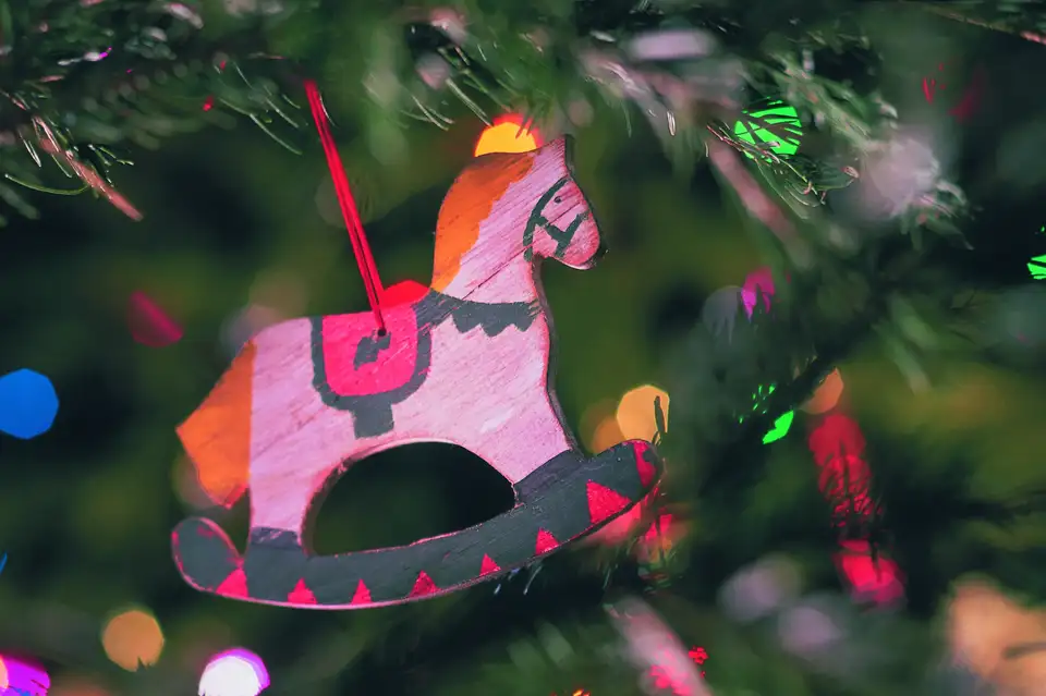 Decorazione a forma di cavalluccio in legno appesa all’albero di Natale con luci colorate