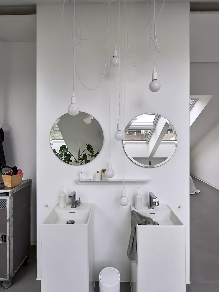 Modernes Badezimmer mit Säulenwaschbecken, runden Spiegeln und einem VELUX Dachflächenfenster.
