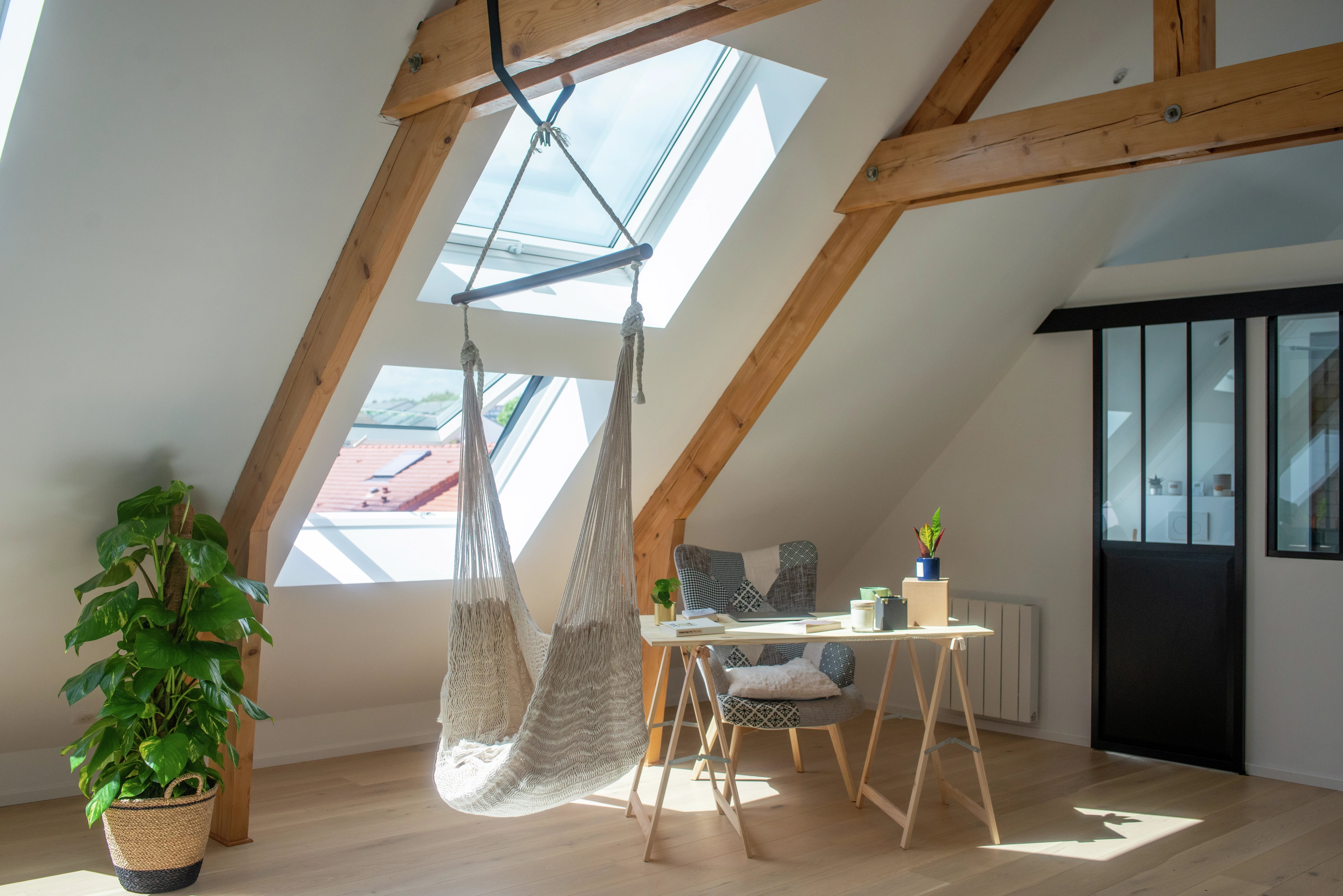 Attic room with sloped ceiling, VELUX window, hammock chair, and desk.