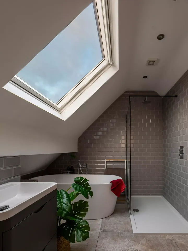 Zeitgemäßes Badezimmer mit VELUX Dachflächenfenster, freistehender Badewanne und begehbarer Dusche.