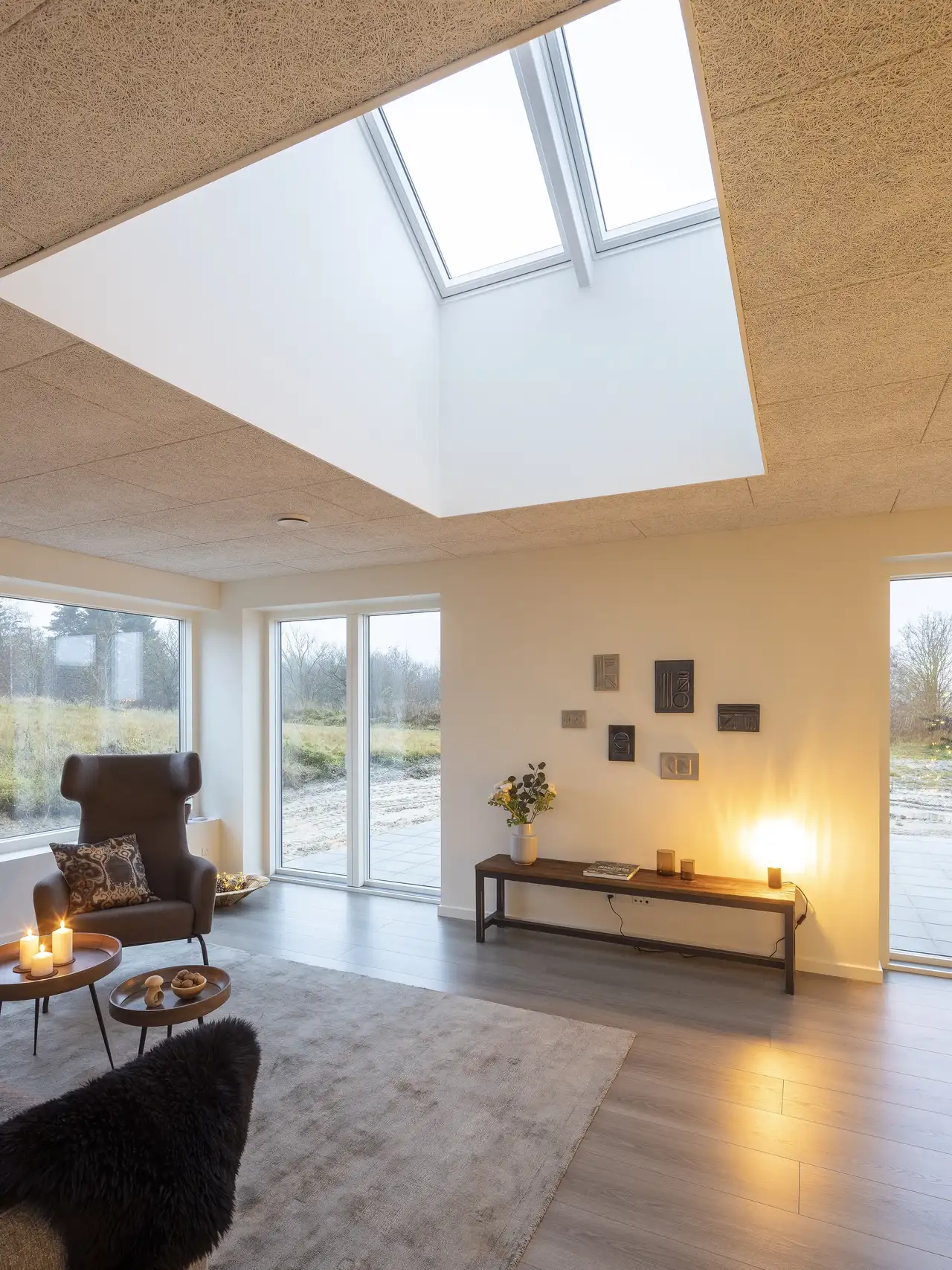 Salon lumineux avec grandes fenêtres verticales et fenêtres de toit.