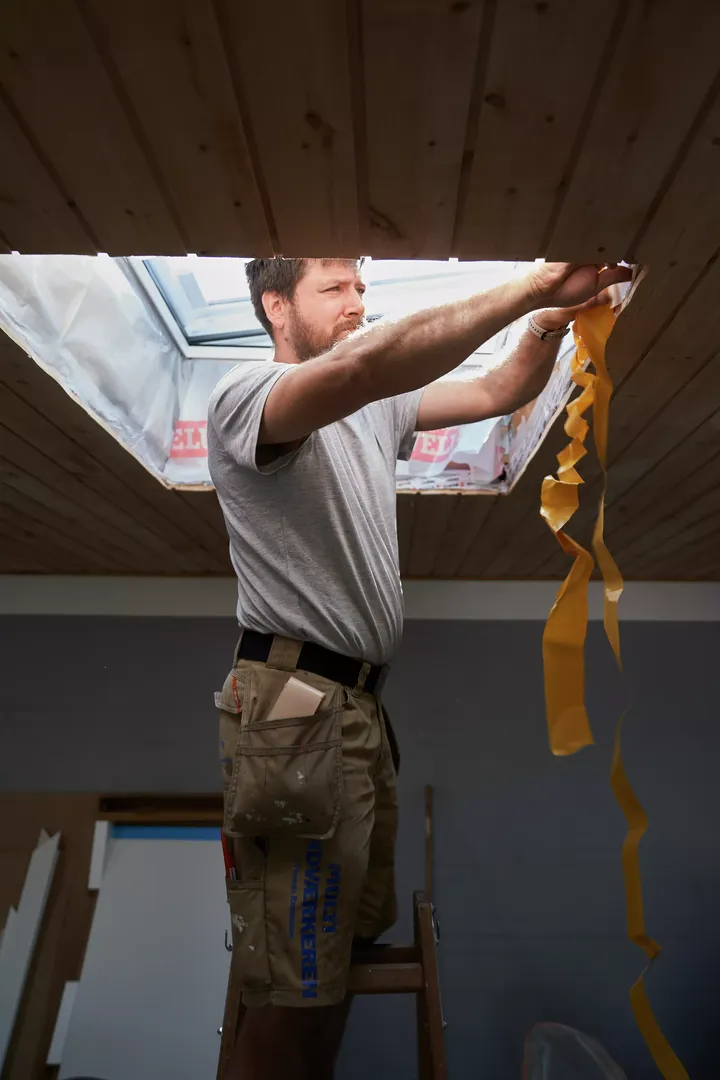 Handwerker hantiert mit der Schutzfolie eines Flachdach-Fensters von VELUX | VELUX Magazin