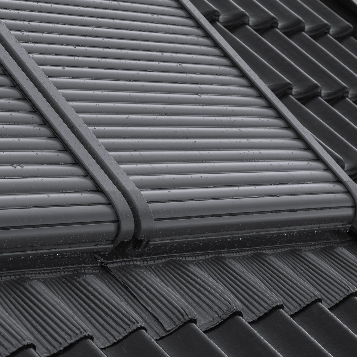 Modern roof with dark tiles and closed VELUX roof window.