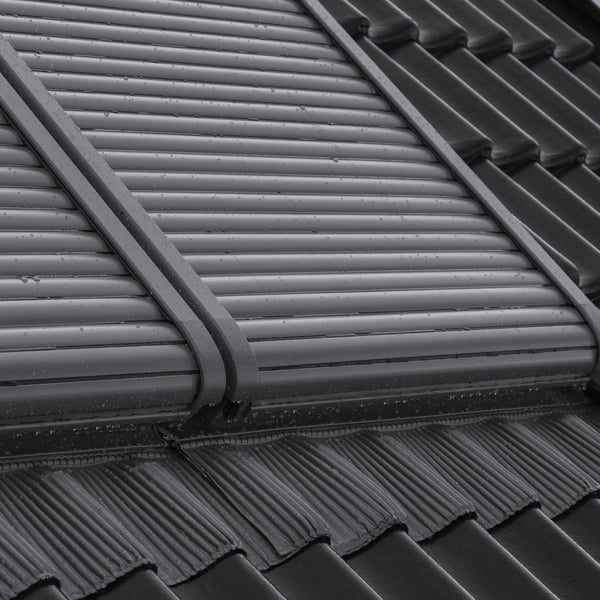 Modern roof with dark tiles and closed VELUX roof window.