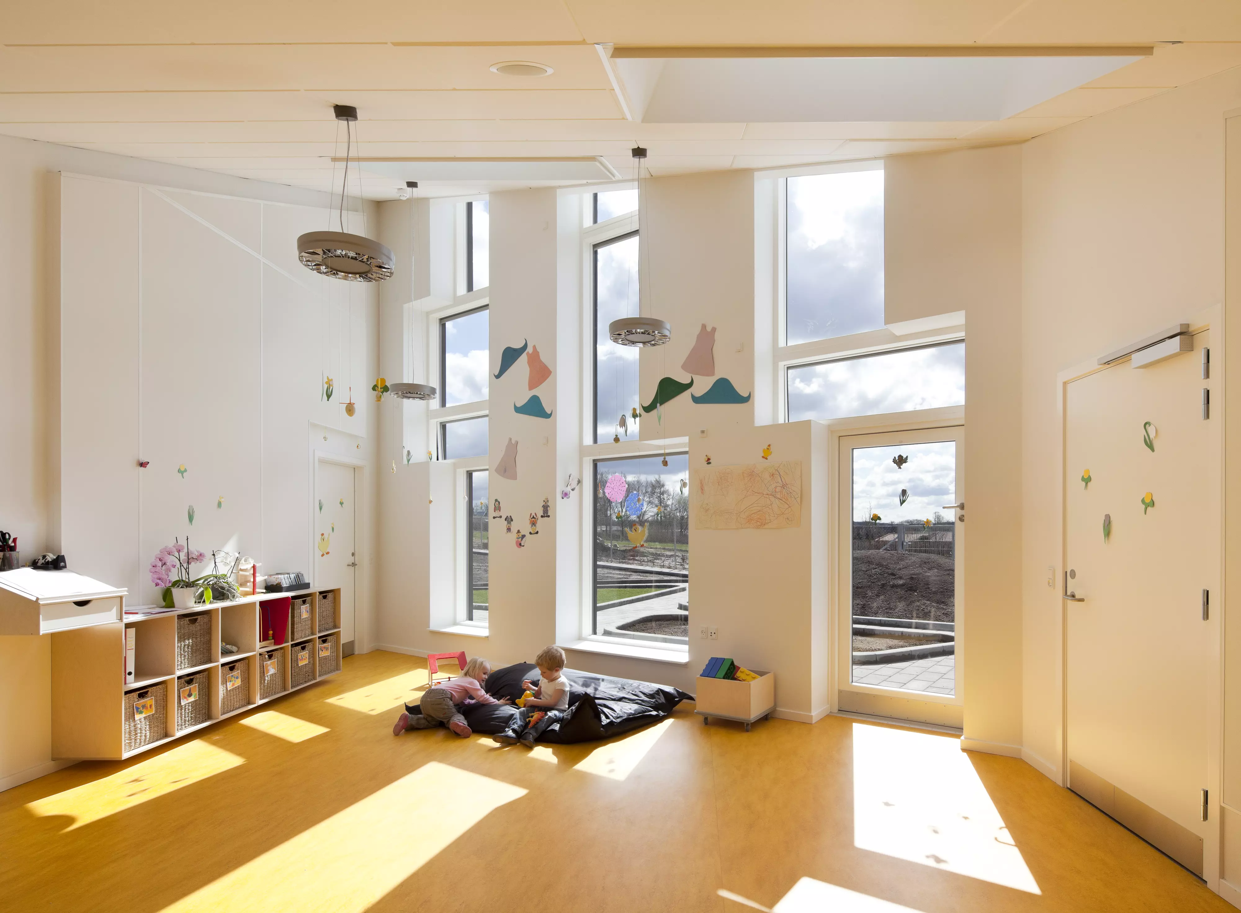 Kids room with large windows, colorful decor, and wooden flooring.