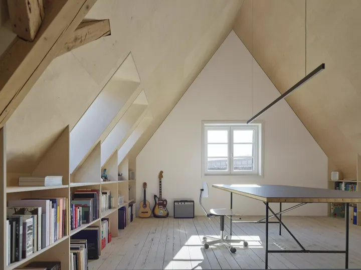Helles und dezent eingerichtetes Dachgeschoss mit Schreibtisch und Stuhl in der Mitte des Raumes | VELUX Magazin