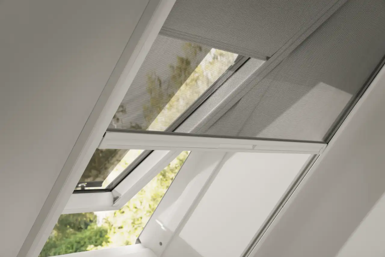 Détail d’une fenêtre de toit VELUX ouverte avec moustiquaire installée sur l’embrasure. 