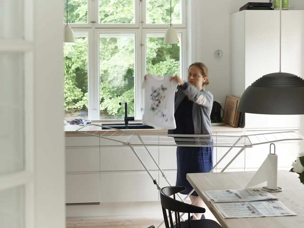 Donna stende il bucato su uno stendino in cucina | Rivista VELUX