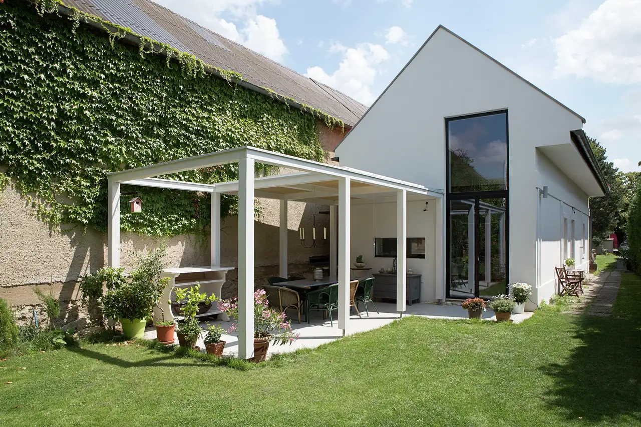 Seitenansicht: Modernes Haus mit Garten neben Hauswand mit Fassadenbegrünung | VELUX Magazin