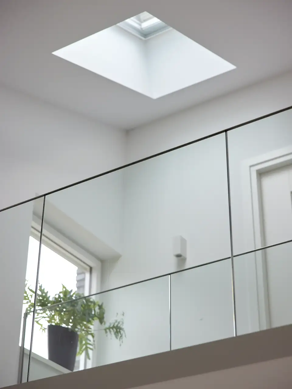 Interieur met VELUX dakraam, glazen balustrades en een kamerplant.