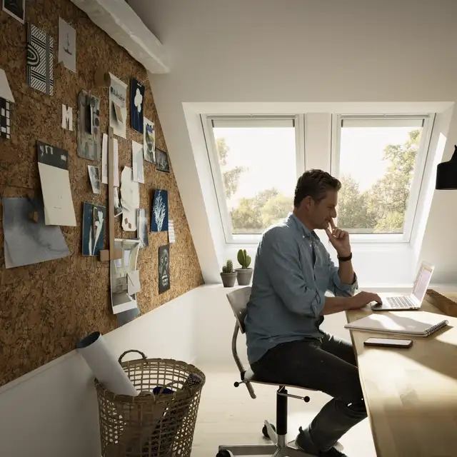 Man sitting by a computer in a room with VELUX roof windows