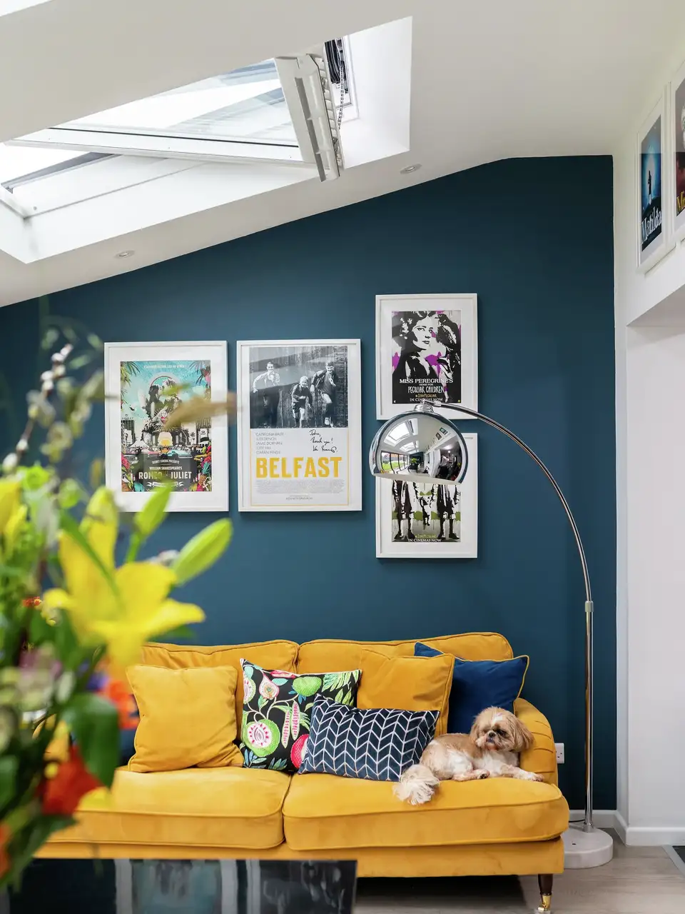 Living room with yellow sofa, VELUX windows, and vibrant decor.