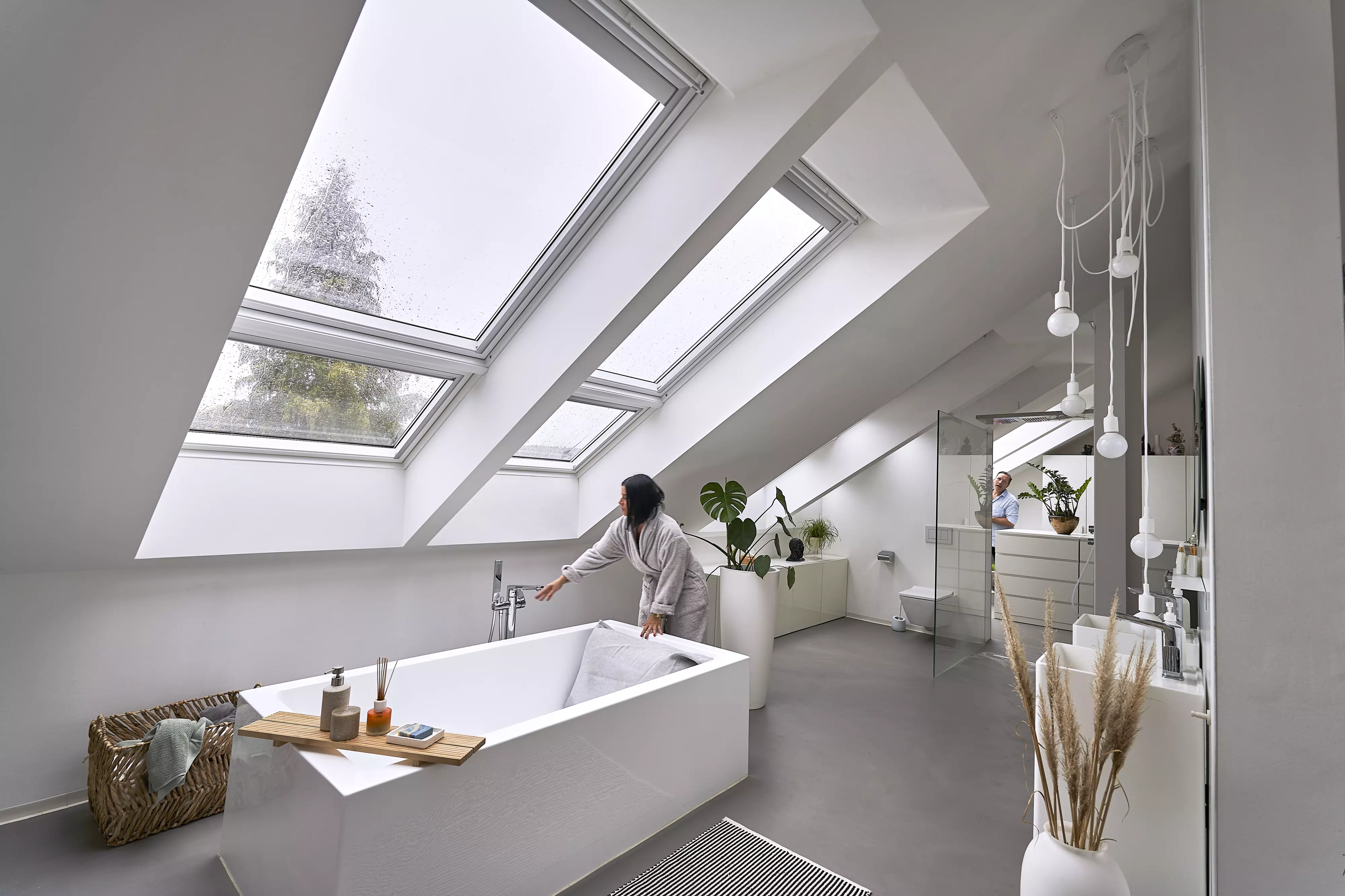 Modernes Badezimmer im Dachboden mit VELUX Dachflächenfenster und weißer Badewanne.