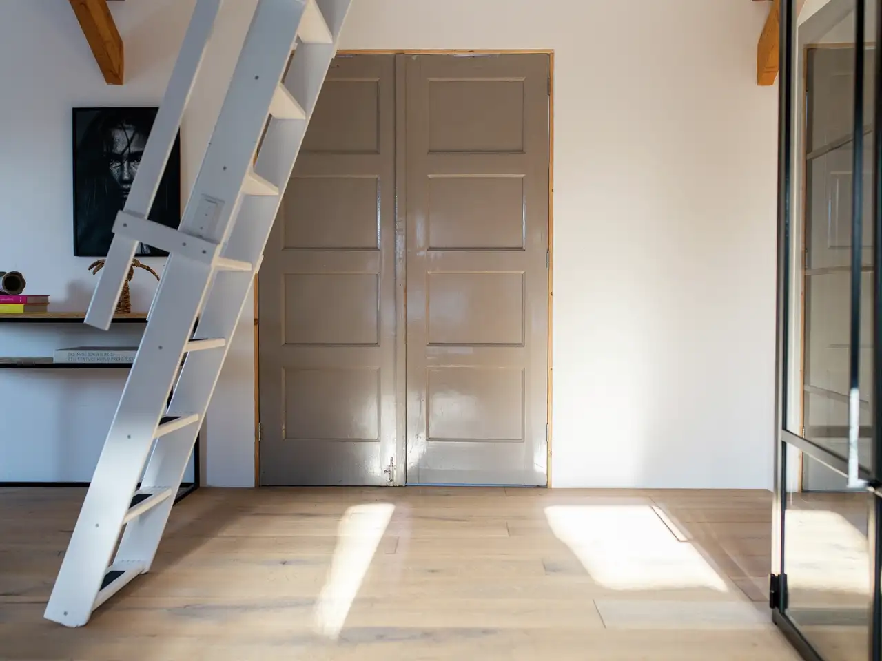 Scala estraibile in legno bianco per l'ultimo piano davanti a una porta grigia | Rivista VELUX