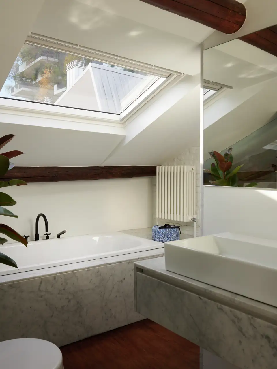 Un bagno in mansarda con vasca sotto finestra per tetti.