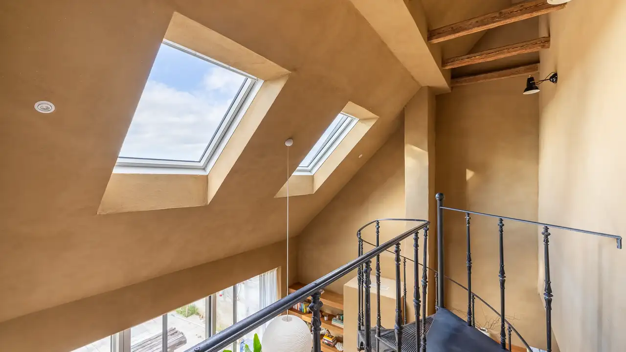Ein heller Zwischengeschossbereich mit VELUX Dachfenstern, die natürliches Licht in das warm getönte Interieur bringen. | VELUX Magazin