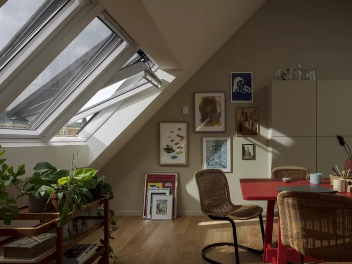 Dachboden-Heimbüro mit VELUX-Fenster, Kunst an den Wänden und hölzernen Möbeln.