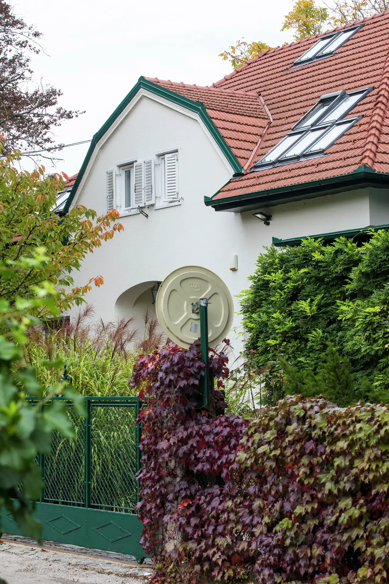 Front view of a house surrounded by greenery and flowers, highlighting roof windows on the upper level. | VELUX